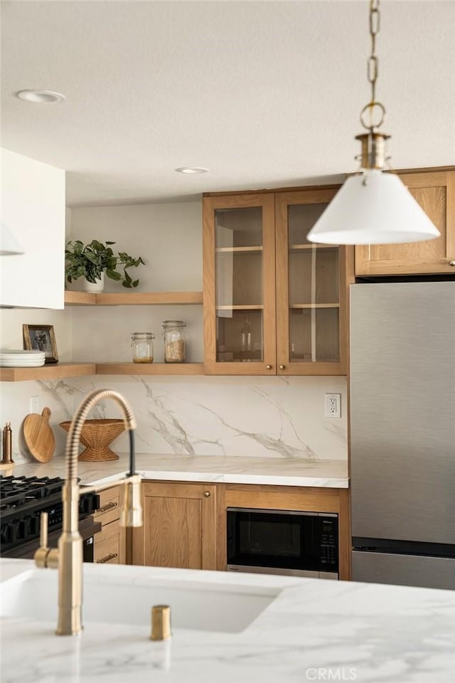 kitchen featuring brown cabinets, decorative backsplash, glass insert cabinets, freestanding refrigerator, and built in microwave