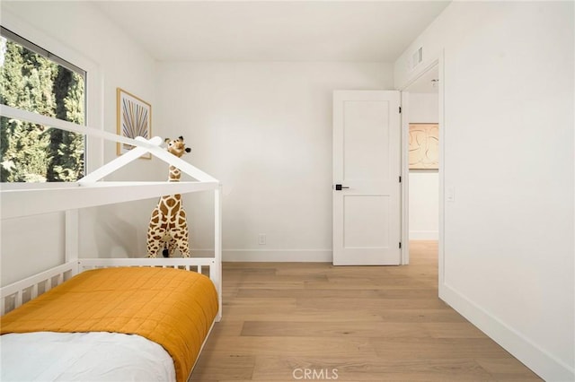 bedroom featuring baseboards, visible vents, and light wood finished floors