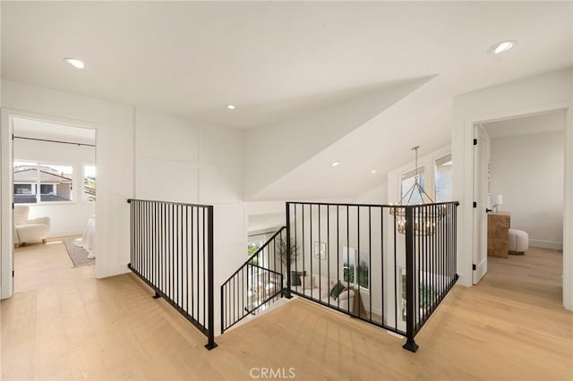 corridor featuring an upstairs landing, light wood-style flooring, and recessed lighting