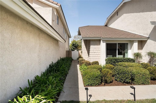 view of side of property with a shingled roof and stucco siding