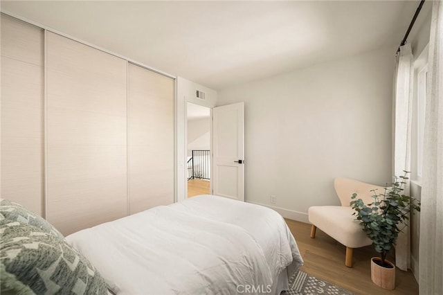 bedroom featuring a closet, visible vents, baseboards, and wood finished floors