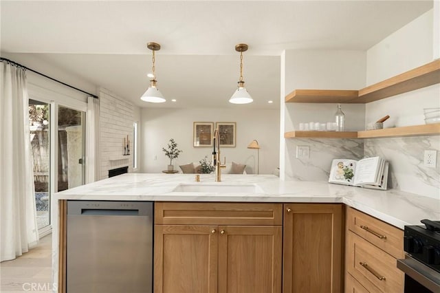 kitchen featuring light stone counters, a peninsula, a sink, appliances with stainless steel finishes, and backsplash