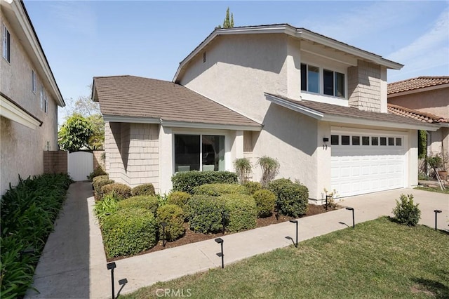 view of front of property with concrete driveway, an attached garage, fence, and stucco siding