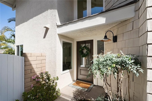 entrance to property with fence and stucco siding