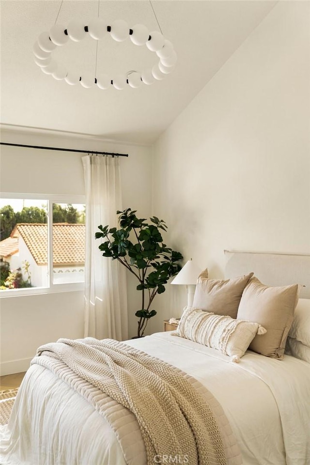 bedroom featuring lofted ceiling, baseboards, and wood finished floors