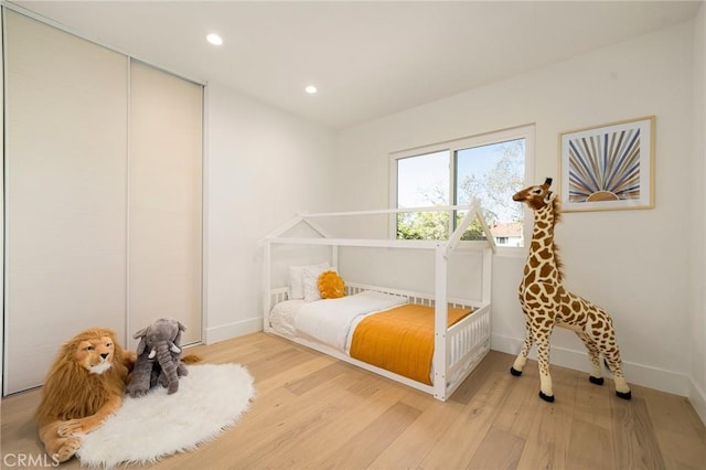 bedroom with light wood-style flooring, baseboards, a closet, and recessed lighting