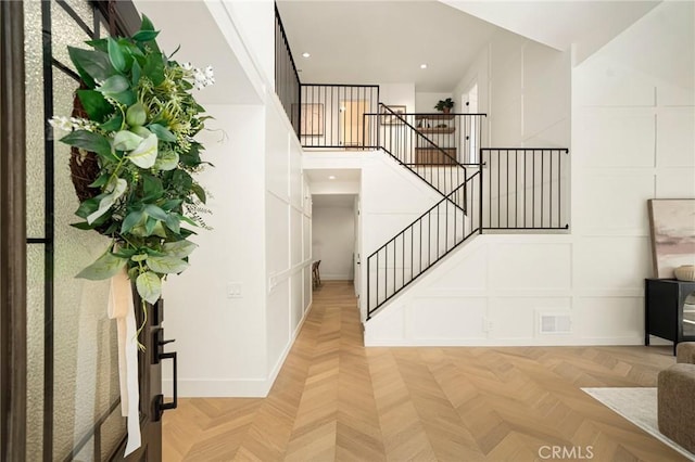 staircase featuring a high ceiling, recessed lighting, visible vents, and a decorative wall