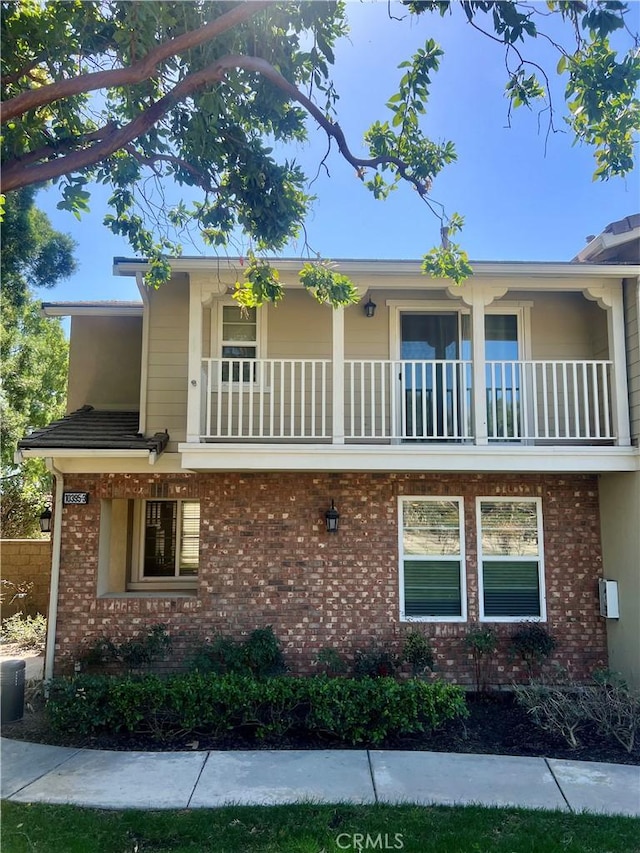 exterior space featuring brick siding and a balcony