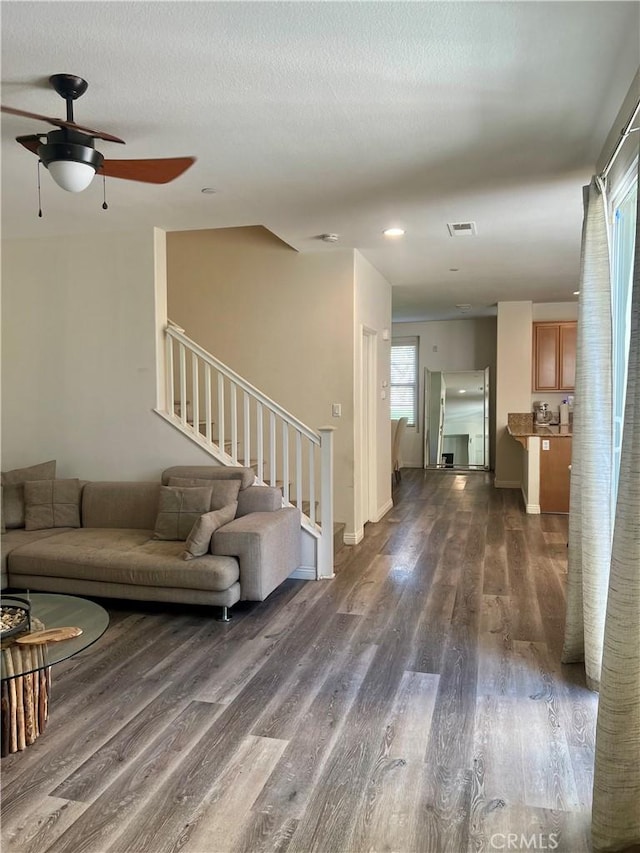 living area featuring visible vents, stairway, a ceiling fan, a textured ceiling, and wood finished floors