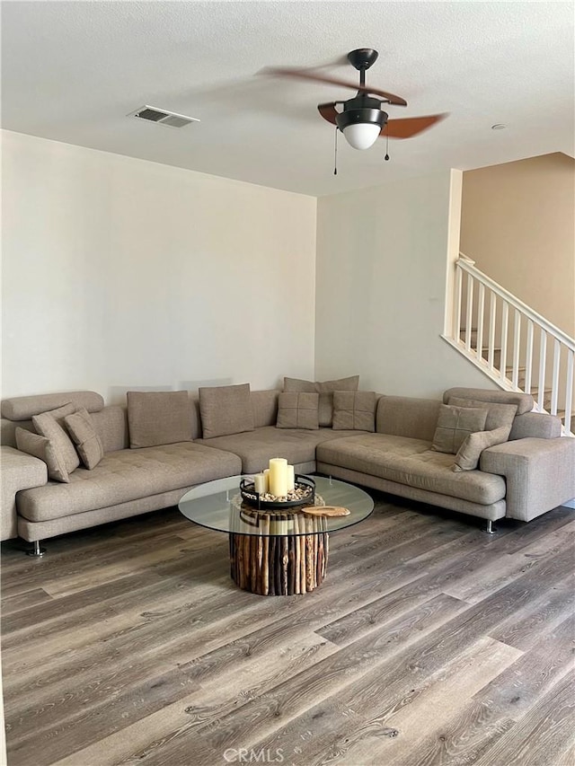 living area with a textured ceiling, stairs, visible vents, and wood finished floors