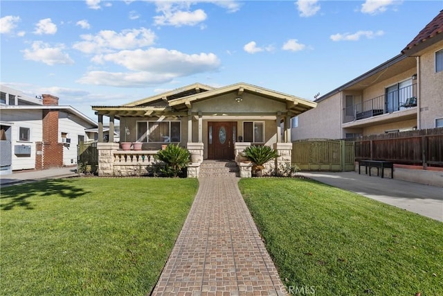 view of front of property featuring stucco siding, a gate, fence, and a front yard