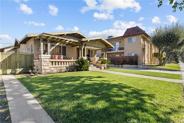 view of front of property featuring a front yard, fence, and stucco siding