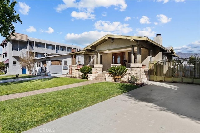 view of front of house with a front lawn, a chimney, a gate, and stucco siding