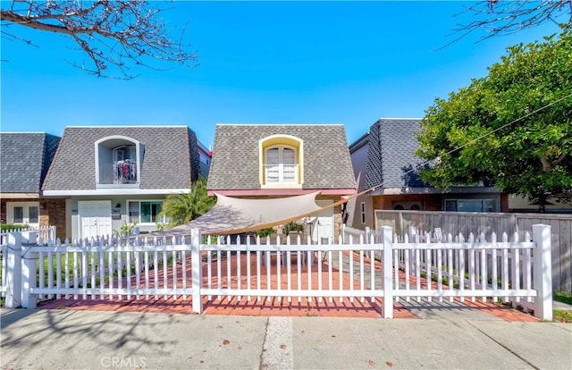 front of property featuring a fenced front yard and a shingled roof