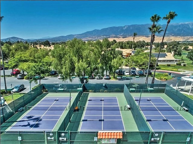 view of tennis court featuring a mountain view and fence