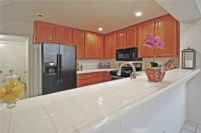 kitchen featuring tile countertops, black appliances, a peninsula, and recessed lighting