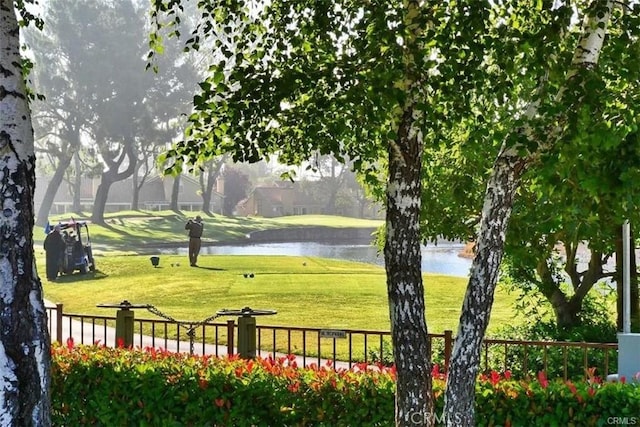 view of property's community featuring fence, a lawn, and a water view