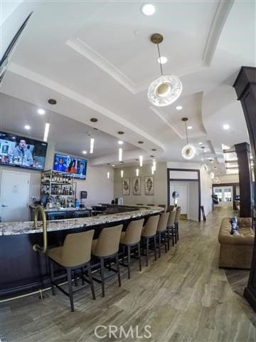 bar with wet bar, a tray ceiling, hanging light fixtures, and recessed lighting