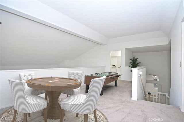 carpeted dining area featuring vaulted ceiling with beams