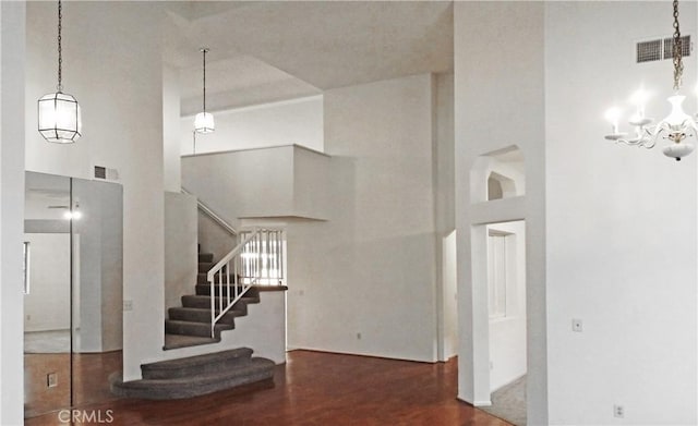 stairs featuring visible vents, a towering ceiling, and wood finished floors