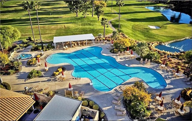 community pool with a patio area, a lawn, and a water view