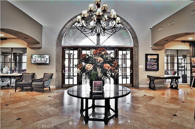 dining space with a wealth of natural light, baseboards, a notable chandelier, and a towering ceiling