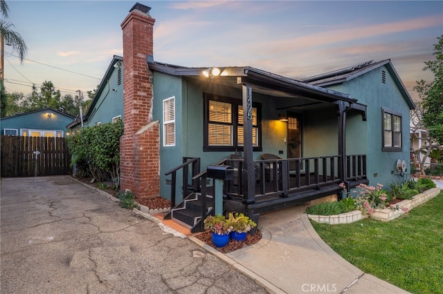 view of front of house featuring fence, a porch, and stucco siding