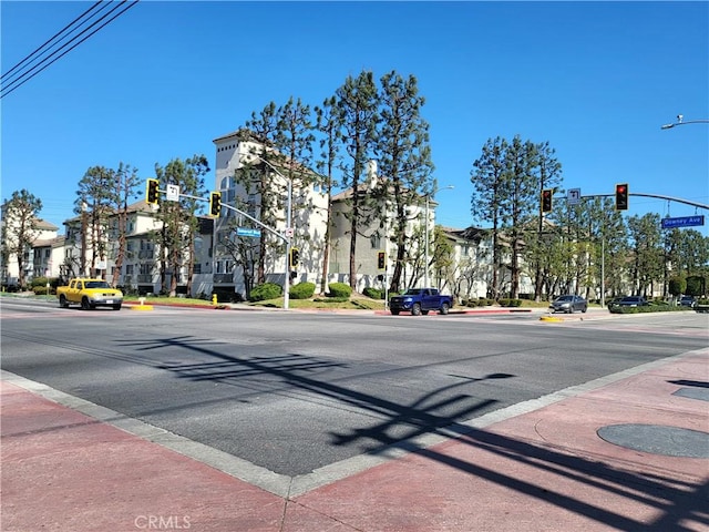 view of road featuring traffic lights, curbs, sidewalks, and street lights