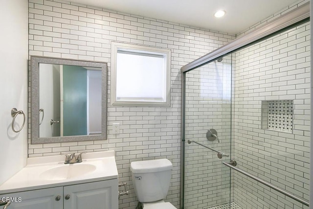 bathroom featuring a stall shower, toilet, vanity, tile walls, and recessed lighting