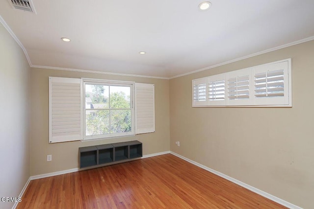 empty room featuring crown molding, wood finished floors, visible vents, and baseboards