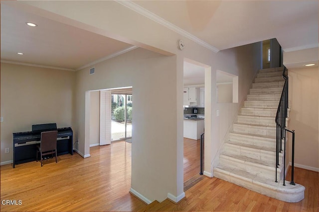 stairway featuring crown molding, baseboards, and wood finished floors