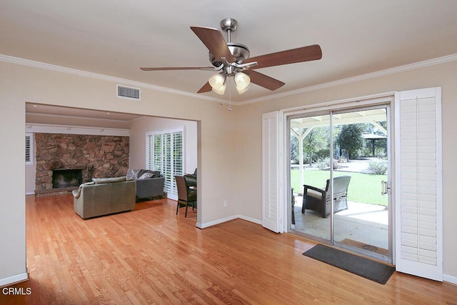 unfurnished living room with light wood finished floors, a fireplace, visible vents, and crown molding