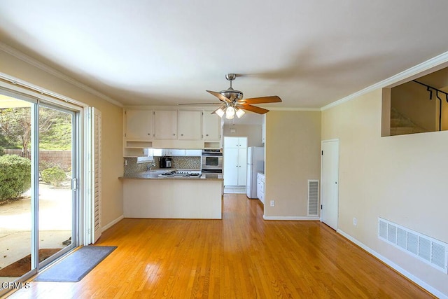 kitchen with visible vents, ornamental molding, light wood-type flooring, backsplash, and freestanding refrigerator