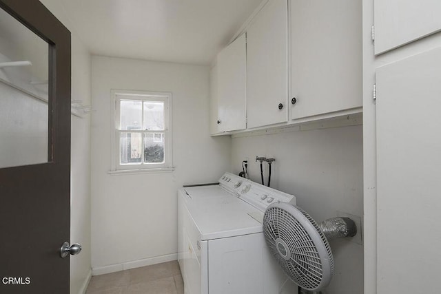 laundry area featuring light tile patterned floors, washing machine and dryer, cabinet space, and baseboards