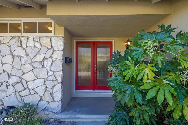 doorway to property featuring stone siding and stucco siding