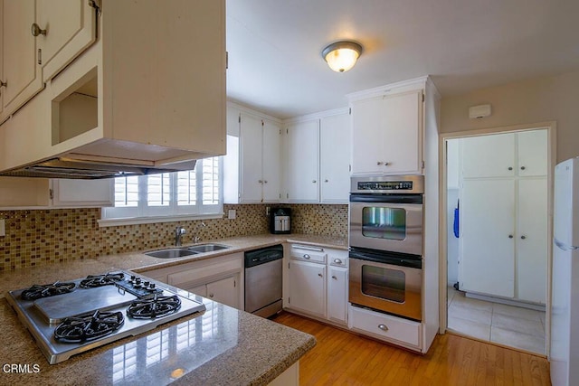 kitchen featuring decorative backsplash, stainless steel appliances, light wood-type flooring, white cabinetry, and a sink