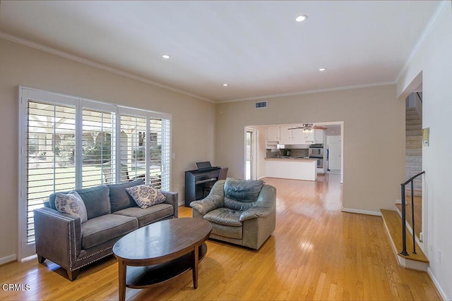 living room featuring stairs, ornamental molding, light wood-type flooring, and visible vents