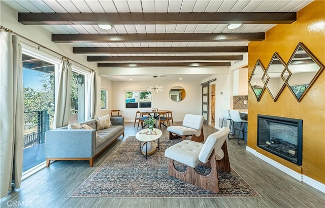 living room with wood finished floors, beamed ceiling, a glass covered fireplace, and baseboards