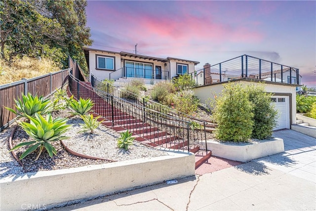 view of front of home featuring a garage, concrete driveway, stairway, fence, and stucco siding