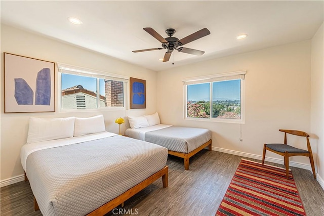 bedroom with multiple windows, wood finished floors, and baseboards