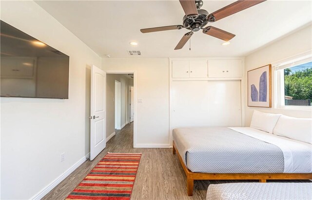 bedroom featuring baseboards, a closet, visible vents, and wood finished floors