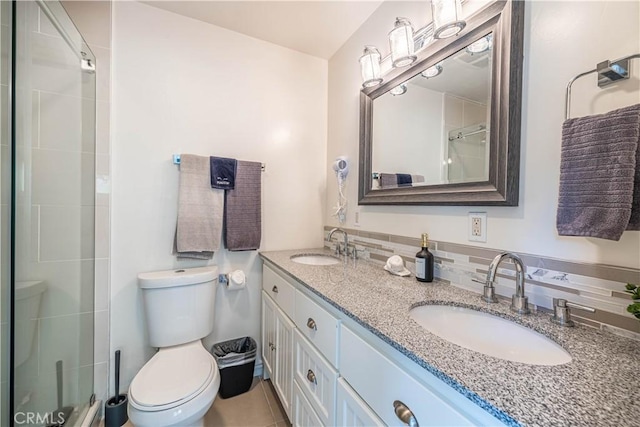 bathroom with tiled shower, a sink, toilet, and double vanity