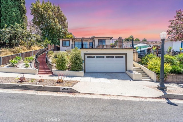 view of front of house with a garage, stucco siding, fence, and stairs