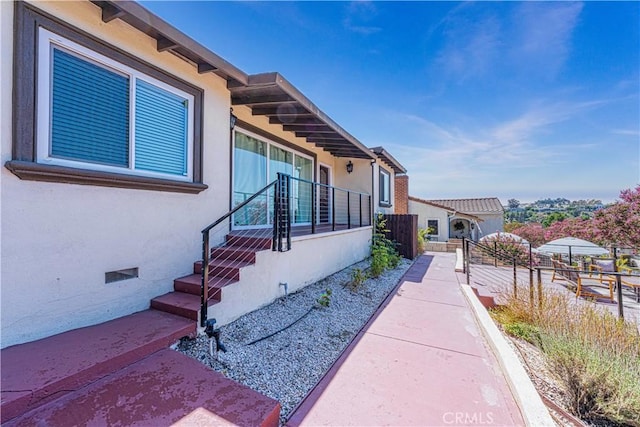 view of side of home featuring crawl space, fence, and stucco siding