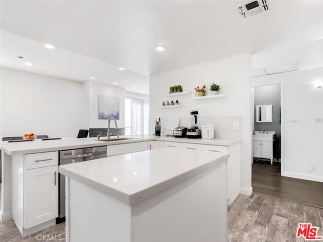 kitchen featuring a peninsula, a sink, light countertops, open shelves, and stainless steel dishwasher