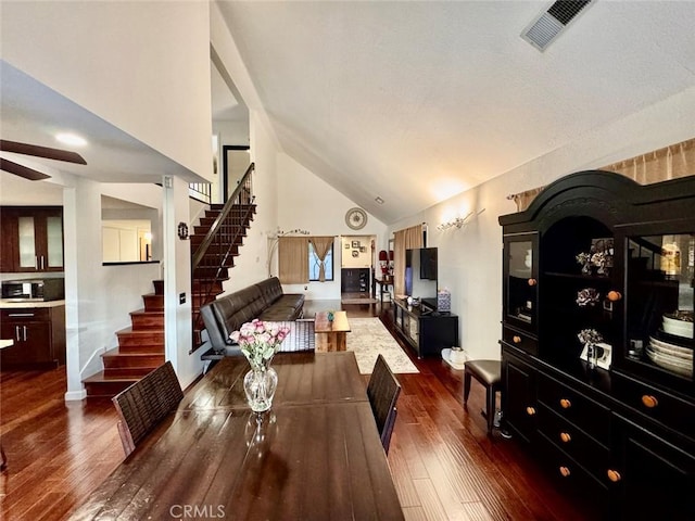 dining area featuring high vaulted ceiling, visible vents, a ceiling fan, stairs, and dark wood-style floors