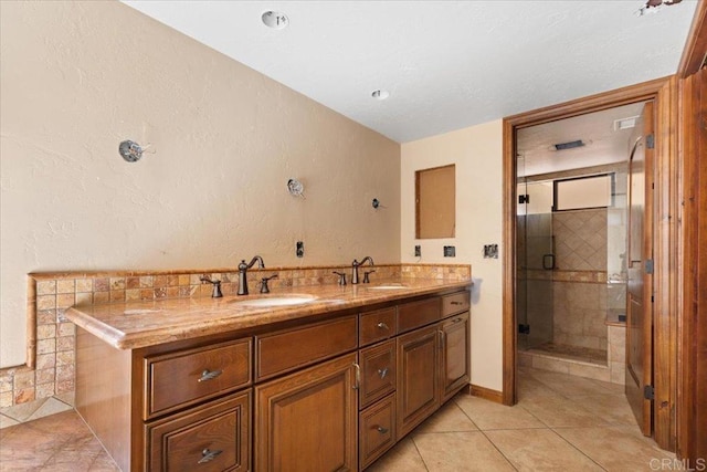 full bath with double vanity, a stall shower, tile patterned flooring, and a sink