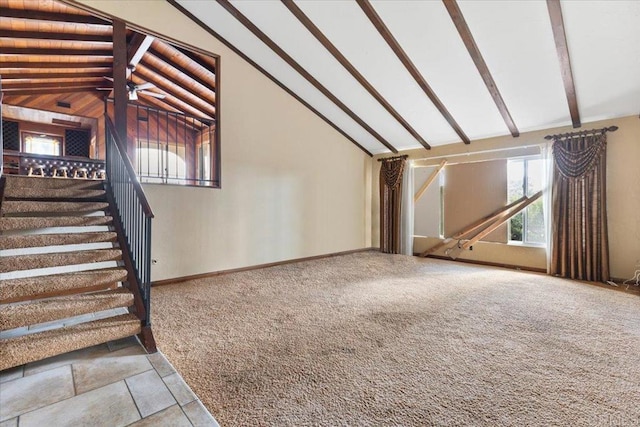 unfurnished living room with lofted ceiling with beams, ceiling fan, carpet flooring, baseboards, and stairway