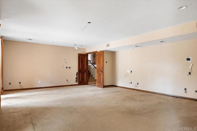 unfurnished room with light carpet, stairs, and baseboards