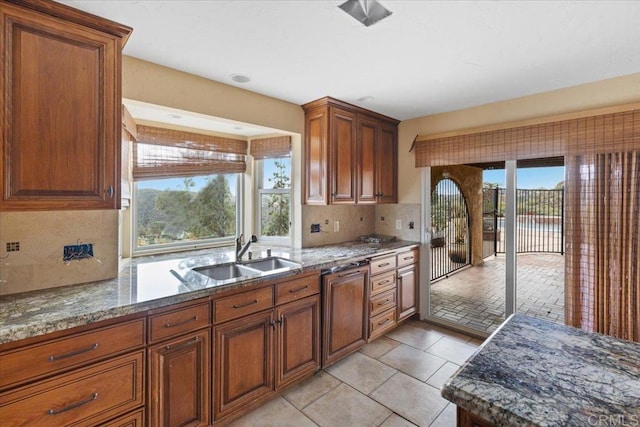 kitchen featuring brown cabinetry, stone countertops, decorative backsplash, and a sink